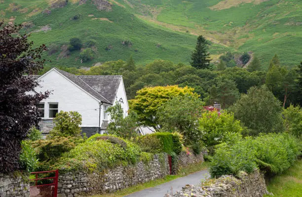 Beautiful white cottage house on the picturesque green farmlands at the village of Borrowdale the Lake District area in United Kingdom