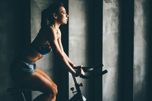 Attractive young woman at the gym riding on exercising bike. stock photo