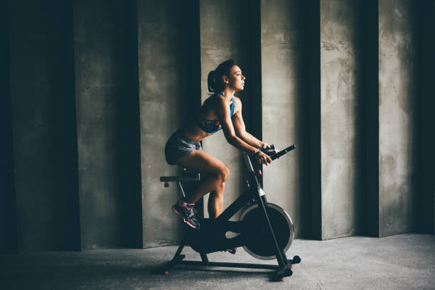 Attractive young woman at the gym riding on exercising bike. stock photo