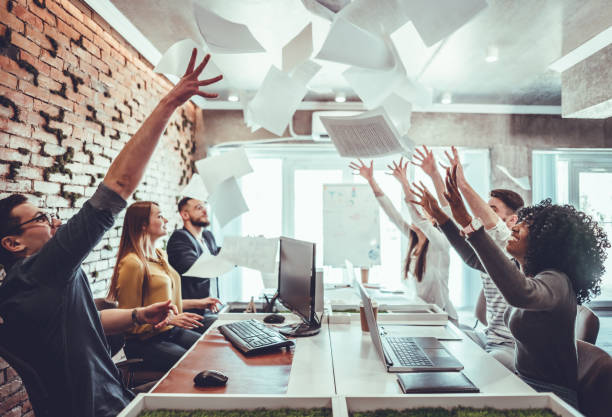 istock Group of young business people throwing documents and looking happy while celebrating success at their working places in startup office 1177497707
