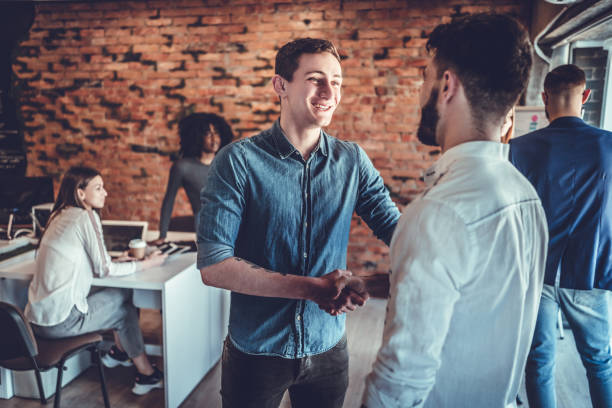 istock Two happy young men shaking hands while standing in the office 1177497725