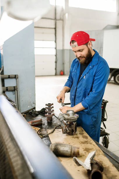 車のエンジンの部品を一緒に固定する若いプロの技術者 - coveralls professional occupation manual worker service occupation ストックフォトと画像