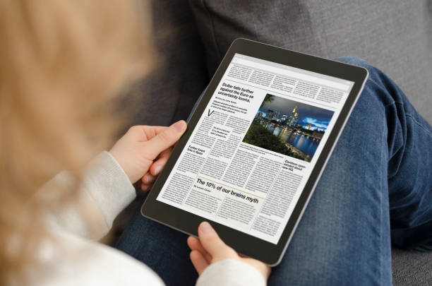 giovane donna che legge l'articolo di notizie su un tablet moderno - newspaper reading holding paper foto e immagini stock