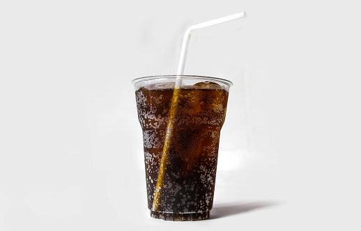 Full glass of cola with ice and curve straw, bubble and fizzy texture, isolated on white background.