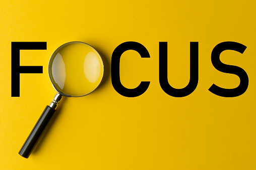 Focus typed on yellow background. O letter replacement with magnifying glass.