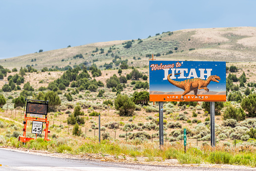 Manila, USA - July 24, 2019: Sign closeup for welcome to Utah near Flaming Gorge National Recreational Area Park with dinosaur image on road highway