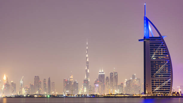 beleuchtete skyline von dubai mit dem burj khalifa und dem luxushotel burj al arab. dubai, vereinigte arabische emirate. - fog desert arabia sunset stock-fotos und bilder