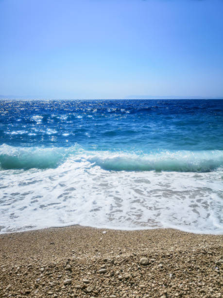 istock Breaking Wave of Blue Ocean on Pebbles beach Summer Background 1177510371