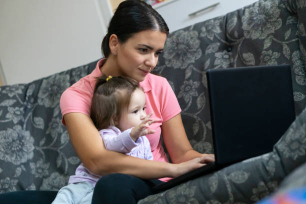 istock Mother  with her baby sitting on a sofa and working on a laptop 1177514437
