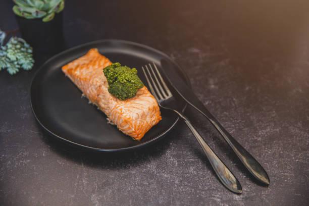 filet de saumon rose rôti grillé sur une assiette noire avec une boule de pesto - wild salmon flash photos et images de collection
