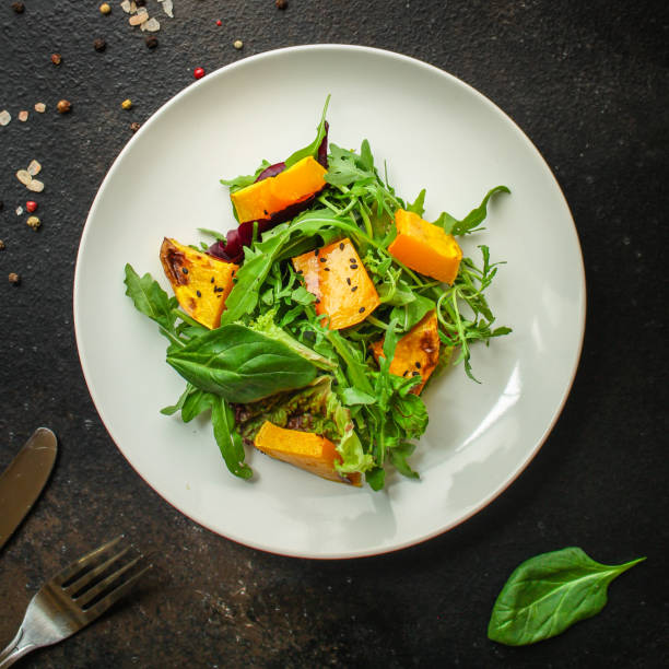 healthy salad pumpkin and mix leaves  lettuce (arugula, spinach, red chard and other ingredients) menu concept. food background. copy space. Top view