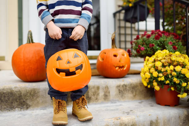 ハロウィーンのお祝いパーティーで小さな男の子。子供はハロウィーンのカボチャジャックオランタンのような形のバケツを持っています。 - single flower flower autumn pumpkin ストックフォトと画像