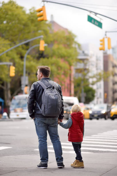 el niño con su padre mira la señal del semáforo en la encrucijada de la ciudad de nueva york, ee.uu. leyes de tráfico. - familia de cruzar la calle fotografías e imágenes de stock