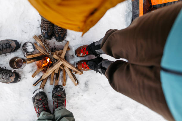 tourists warming by campfire on snow - people cold frozen unrecognizable person imagens e fotografias de stock