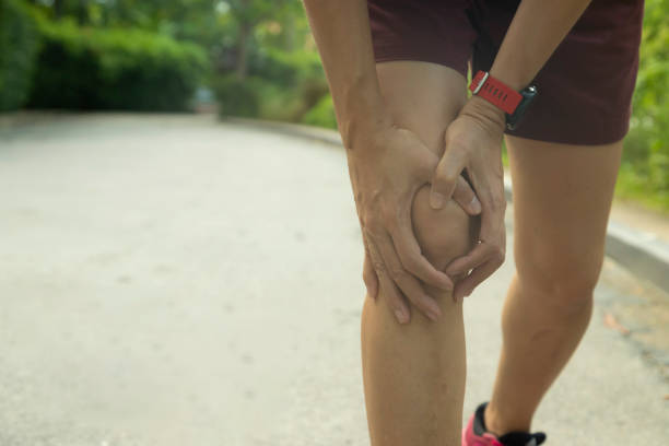 Close-up Asian woman use hands hold on her knee injury. Close-up Asian woman use hands hold on her knee injury while running in the park on morning, Injury from workout concept. physical injury sport ice pain stock pictures, royalty-free photos & images