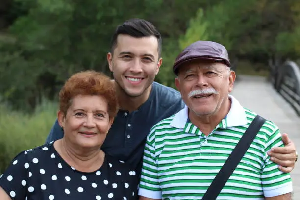 Hispanic man with his parents outdoors.