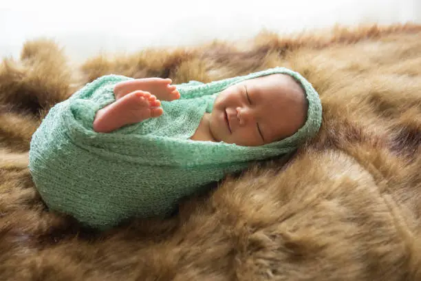 asia Newborn baby sleep and smile on fur brown and green wrap cloth feelgood relaxing isolated on white background