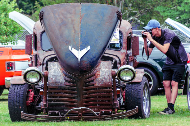 Kingston, Nova Scotia, Canada - August 24, 2019 : Young man focuses his camera to snap a photo of a 1937 Chevrolet rat rod pickup, Autos for Autism Show & Shine in Annapolis Valley region of Nova Scotia.