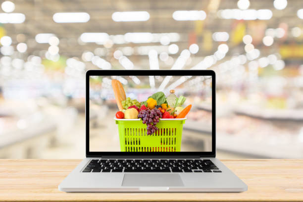istock supermarket aisle blurred background with laptop computer and shopping basket on wood table grocery online concept 1177546607