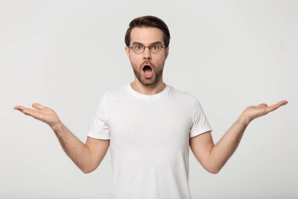 istock Confused millennial guy raised hands near copy spaces for advertises. 1177546774