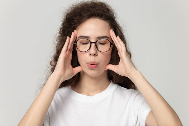 mujer cansada en las gafas masajeando las sienes, tratando de reducir el estrés. - exhalar fotografías e imágenes de stock