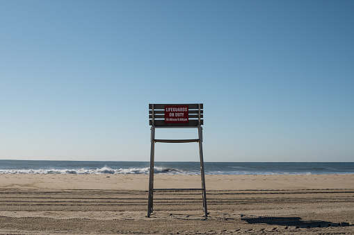 An empty lifeguard chair by itself at the beach