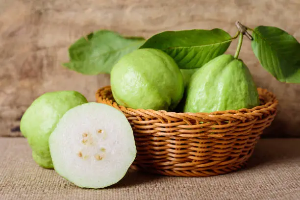 Fresh guava fruit in basket on wooden background, tropical fruit