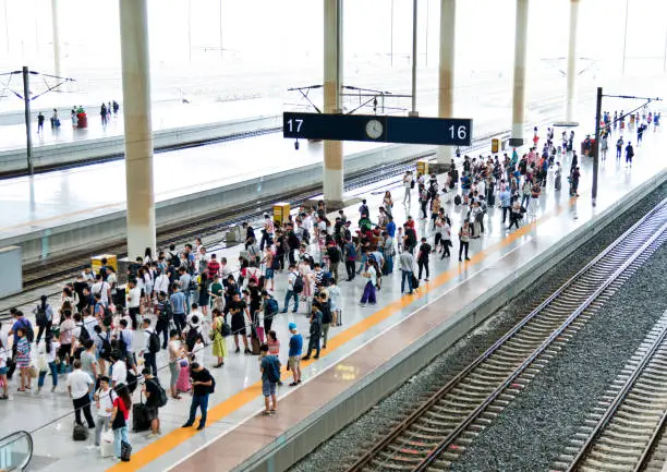 Crowd of passengers waiting on station platform.
