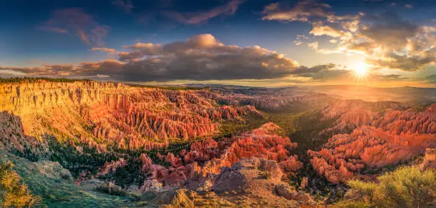 Photo of Bryce Canyon at dawn with shining sun and colorful clouds