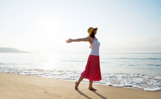 istock Young woman standing on beach with arms outstretched 1177567816