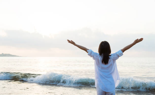 istock Young woman standing on beach with arms raised 1177567817