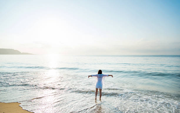 istock Young woman standing on beach with arms outstretched 1177567908