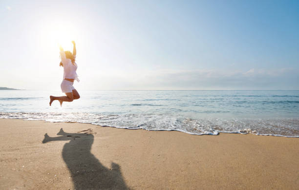 Excited woman jumping at the beach Excited woman jumping at the beach. wave jumping stock pictures, royalty-free photos & images