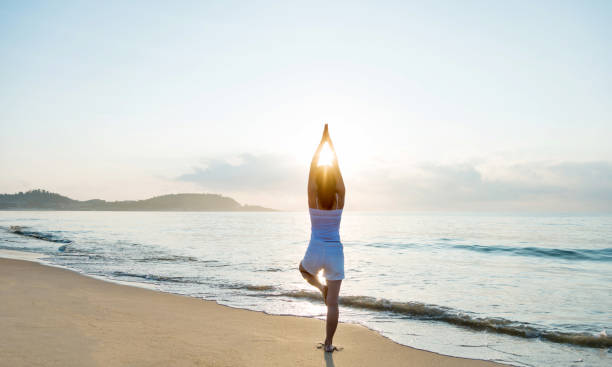 woman doing yoga at the beach - stretch beach imagens e fotografias de stock