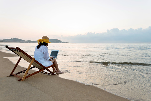 Woman using laptop at the beach.