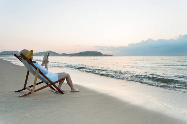istock Woman reading book at the beach 1177569041