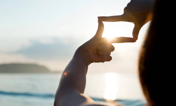 kobieta ręcznie robi ramę wokół słońca - focus finger frame frame human hand zdjęcia i obrazy z banku zdjęć