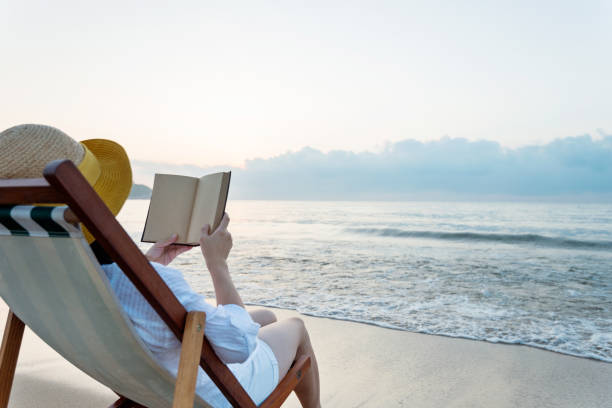 istock Woman reading book at the beach 1177569638