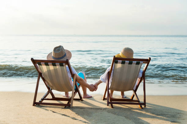 istock Couple sitting on deck chair at beach 1177570641