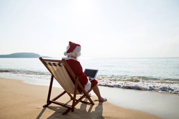 A person dressed as Santa Claus relaxes at home in casual pajamas, reading a book near a beautifully lit Christmas tree.