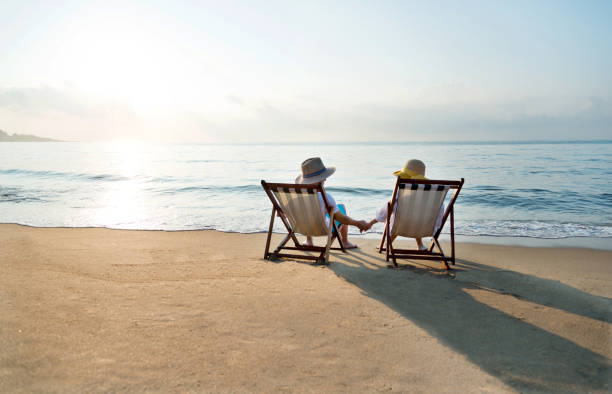 istock Couple sitting on deck chair at beach 1177570856
