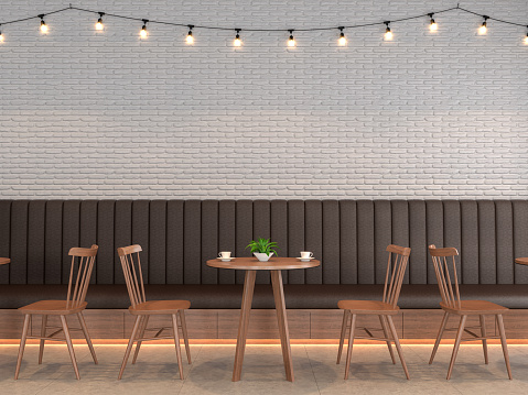 Loft style coffee shop with empty white brick walls decorated with brown leather benches and tables, wooden chairs adorning the walls with string lights.3d render