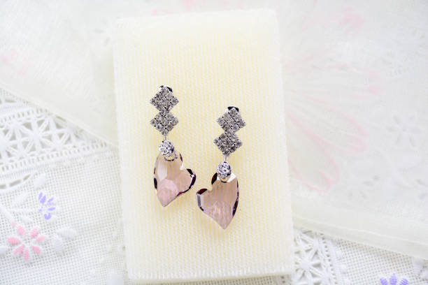 istock Crystal earrings on white fabric background