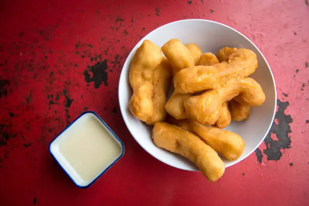 Photo of Patongo (or Chinese Doughnut)with condensed milk on the red table.