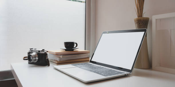 istock Minimal photographer workplace with open blank screen laptop, vintage camera and a cup of coffee 1177575002