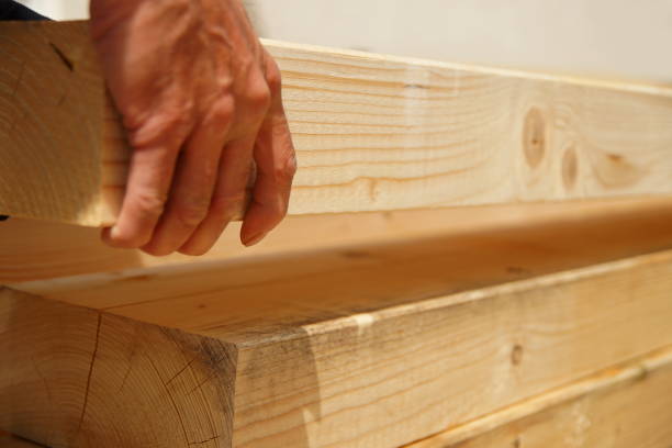 mężczyzna ręka stolarza podnosi naturalną drewnianą belkę na placu budowy. - spruce wood zdjęcia i obrazy z banku zdjęć