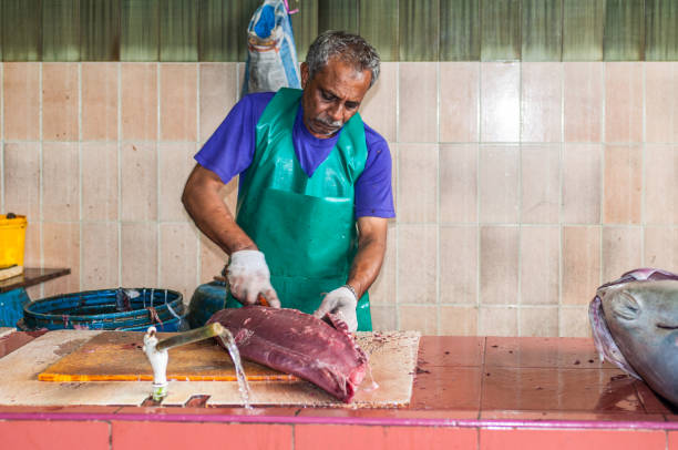 Fish Market in the city of Male, capital of Maldives Male, Maldives - November 16, 2017: Man cutting big tuna fish for sale at the Fish Market in the city and island of Male, capital of Maldives. maldives fish market photos stock pictures, royalty-free photos & images