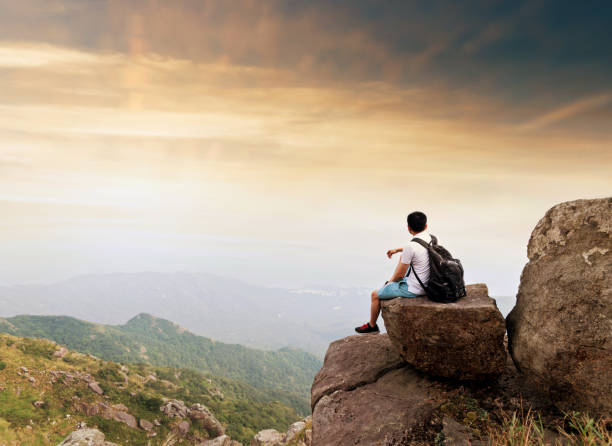 istock Man backpacker sitting on the top of mountain at sunset 1177586869