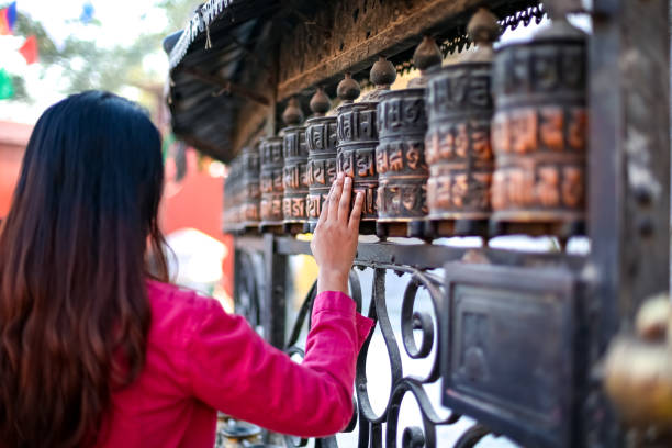 Young girl passing by Buddhist prayer wheel Young girl passing by Buddhist prayer wheel buddhist prayer wheel stock pictures, royalty-free photos & images