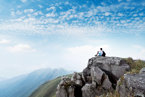 Man backpacker sitting on the top of mountain.